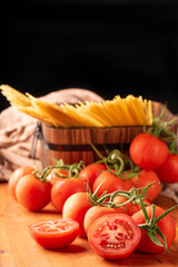 Pasta, beautiful details of red tomatoes and strands of raw spaghetti over rustic wood, selective focus.