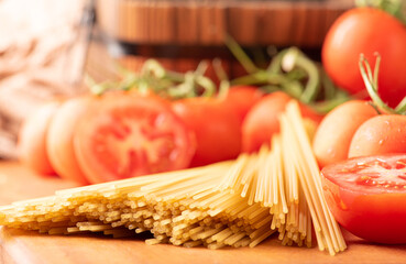Pasta, beautiful details of red tomatoes and strands of raw spaghetti over rustic wood, selective...