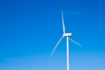A wind turbine in blue sky with motion blurred blades