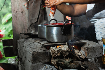 latin peasant cooking rice on an artisan stove made of bricks and ashes. stove lit with dry wood as...