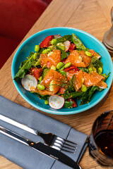 salad with salmon in a restaurant on a blue plate