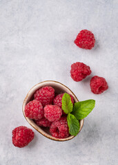 Juicy forest raspberry with mint leaf i a bowl on a light textured background. Healthy food concept