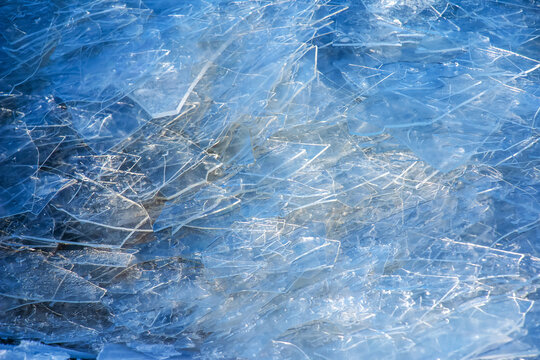 Winter background of the icy surface of the river. Texture of ice covered with snow.