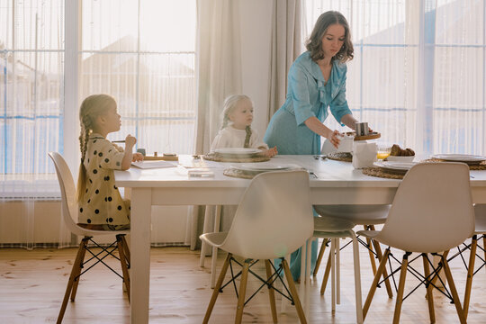 Little girl doing homework at a kitchen table with her mother
