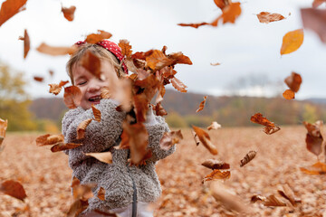 Happy child playing with Autumn leaves