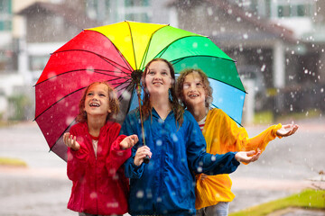 Kids play in rain. Children walk in rainy weather