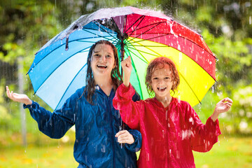 Kids play in rain. Children walk in rainy weather