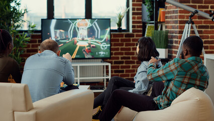 Multiethnic group of people enjoying video games play, having fun with gaming competition on television console. Playing online shooting challenge on tv, leisure weekend activity.