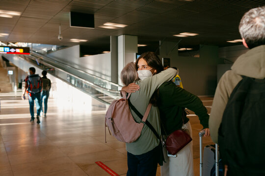 Two women hugging goodbye in airport terminal 
