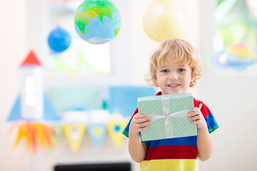 Space theme kids birthday party. Boy with present.