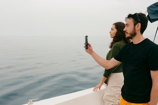 Young couple aboard small vessel taking picture  on smartphone