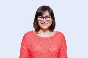 Obraz premium Smiling middle aged female looking at camera on light studio background