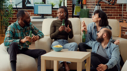 Diverse group of people talking about memories and laughing in living room, having fun and drinking beer. Having conversation and chatting, enjoying friendship positivity. Tripod shot.