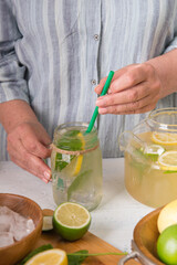 woman  make homemade lemonade with fresh yellow lemons and green mint. closeup photo