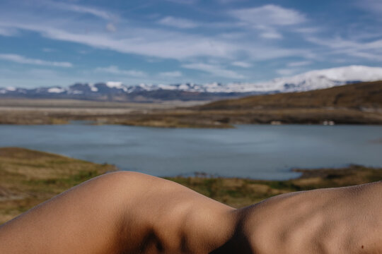 Nude woman lying in front of the lake and snowy mountains in Iceland