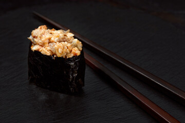 Warm rolls with tuna, salmon, perch, eel, tobiko caviar, nori, rice, cucumber on black background.