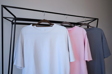 Empty pink gray and white t-shirt on a hanger on a light background. Style and store design concept. Space for copy. Clothes on hangers