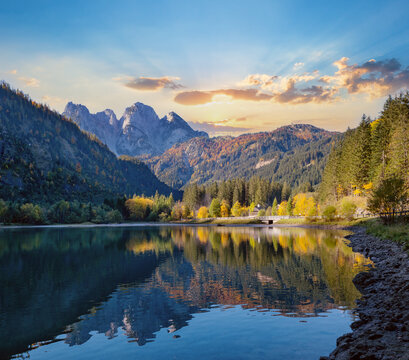 Peaceful autumn Alps mountain lake with clear transparent water and reflections. Gosauseen or Vorderer Gosausee lake, Upper Austria. Dachstein summit and glacier in far.