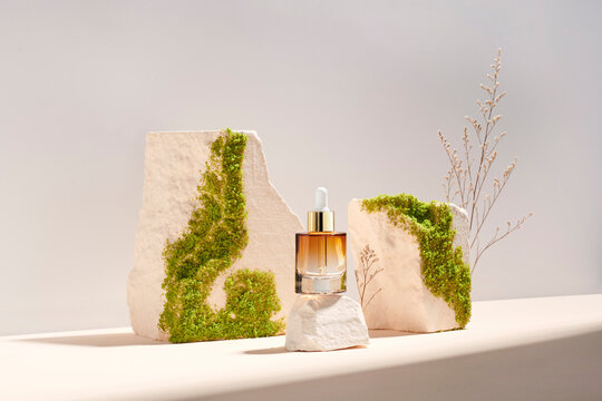 Bottle with oil on stone podium and pastel background
