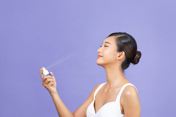 Beautiful woman applying spray water treatment on face