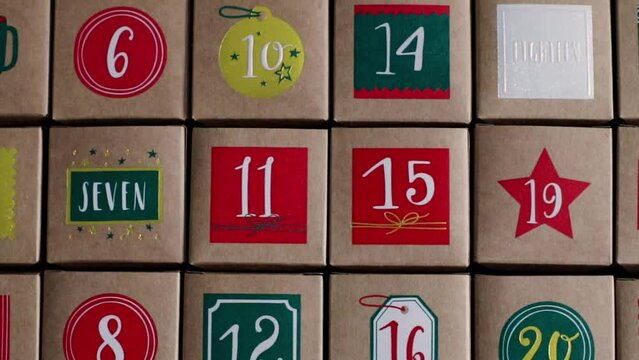 Beautiful advent calendar craft boxes with numbers on the table, flat lay close-up in slow motion and tracking to the right.