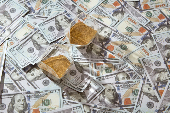 Close up of hourglass on bunch of dollars.