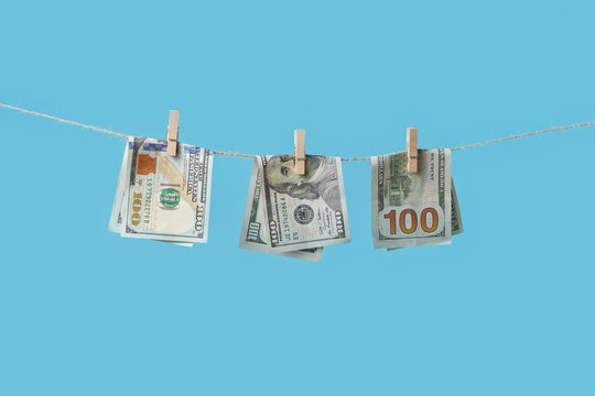 Hundred dollar bills hanging on clothesline.