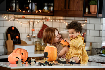 Multi-ethnic family with small child carving a pumpkin preparing it for Halloween holiday, making jack-o-lantern