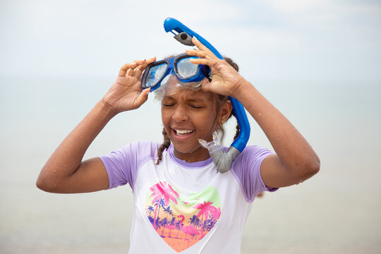 Young girl taking off her googles and snorkel