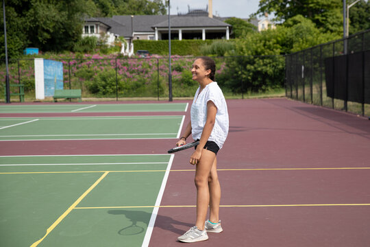 Teen girl standing on a tennis court , looking at her oponent.