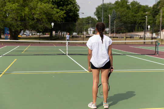 Teen Girl Standing On A Tennis Court , Looking At Her Oponent.