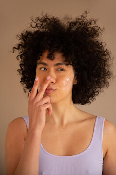 Woman applying moisturizer to her nose tip