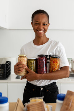 Female volunteer holding canning jars in kitchen