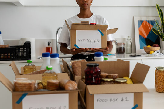 Crop volunteer holding food boxes in kitchen