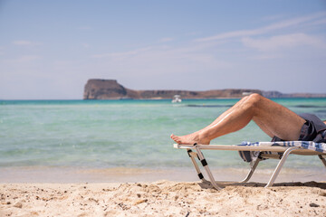 Man Legs On The Sun Bed On The Beach