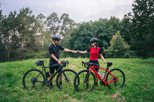Male and female bicyclists bumping fists