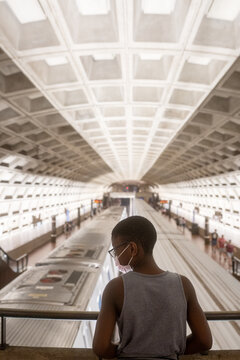 Masked Boy looks at trains in underground station