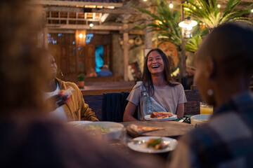 Casually dressed woman laughing with friends at dinner