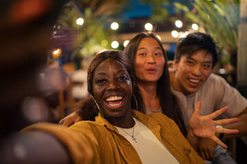 Three friends smiling for selfie together at tropical venue