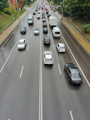 A variety of cars drive on an asphalt two-way road in perspective in the city