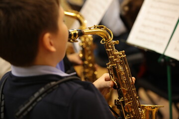 A student playing the saxophone in an orchestra background image details of a musical instrument close-up