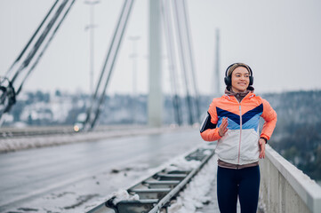 Obraz premium Woman running on the bridge at winter and snow.