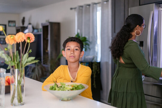 Child with salad bowl in kitchen portrait