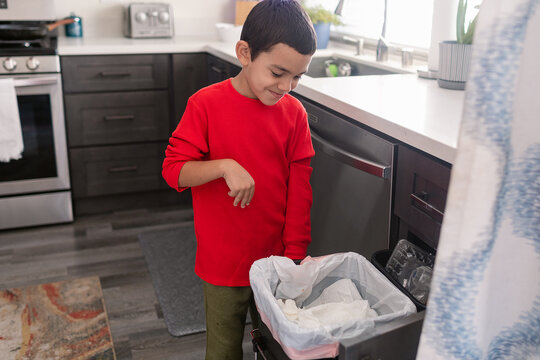 Young boy using recycling bins in kitchen