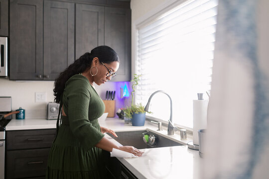 Mixed race woman wearing glasses cleaning the kitchen