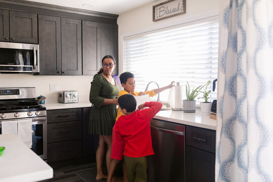 Mother and sons washing hands in kitchen