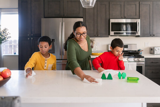 Single Parent Family Cleaning Countertop In Kitchen