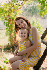 Fototapeta premium Mother and daughter embrace in the park. Woman and little girl spend time together outdoor. Mom and her child. Family concept