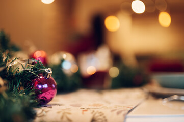 Close up of balls and ornaments on christmas table setting with bokeh lights