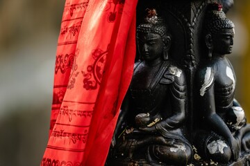 Black Buddha idol statue with red prayer flags in Durbar Square Kathmandu, Nepal